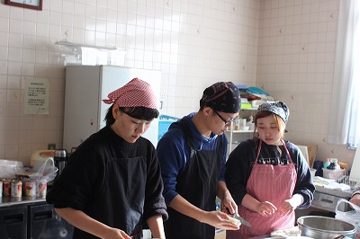 写真：炊き出しのメニュー「チキンのトマト煮」を調理する学生