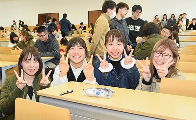 笑顔でピースをしている4人の学生