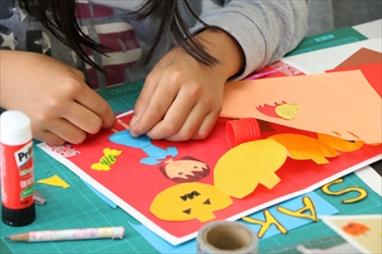写真：カラフルな台紙に色画用紙を貼る児童