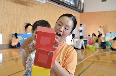 写真：手作りブロックを積み重ねる子どもの補助をする学生