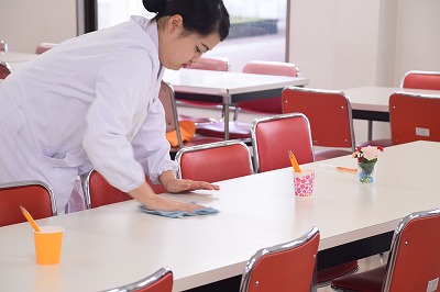 写真：食事を提供する机の上を清掃する学生