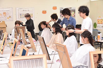 写真：美作大学七夕ヘアアレンジ。忙しそうに学生のヘアアレンジをする美容師
