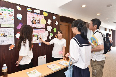 写真：栄養学科ブース前で学科の特徴や栄養士について説明する学生スタッフ2名