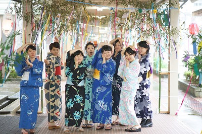 写真：a通路でポーズを決める女子学生の集団。全員自作の浴衣を着用。七夕飾りの下で横並び