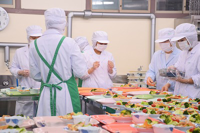 写真：大量調理中、提供手順や作業手順を確認し、作業にあたる担当学生