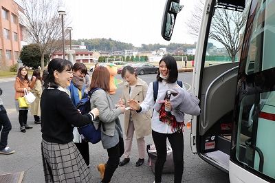写真：バスの前で笑顔で会話する学生と教員