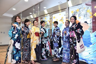 写真：a玄関前で7名の女子学生。横並び