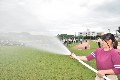 写真：放水ホースを使い放水訓練をする女子学生