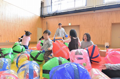 写真：手作りの風船ボールがいっぱいのスペースで子どもたちと遊ぶ学生たち