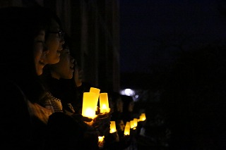 写真：灯かりを手に持って歌う学生たち
