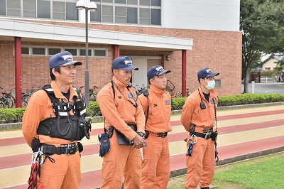 写真：防災避難訓練の様子を見守る消防隊員4人