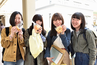 写真：笑顔で買ったものをみせてくれる学生4人