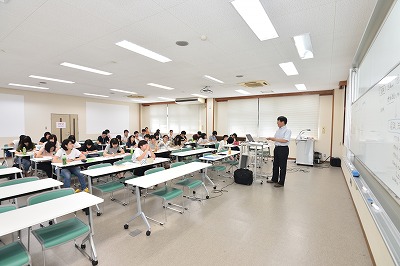 写真：前にたって講義をする作野先生。その話を熱心に聞く学生たち