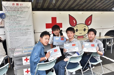 写真：献血バスの前で献血を待つ男子学生