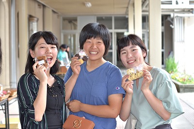 写真：笑顔で買ったものをみせてくれる学生3人