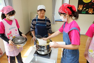 写真：蒸し器で蒸しパンを作る学生と教員