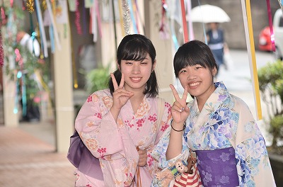 写真：a七夕飾りの下で2人の女子学生。ピースをする