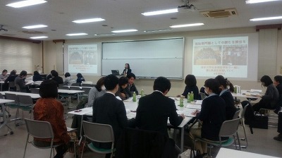 写真：津山市の美作大学内で実施された情報交換会の様子。全体的に後ろから撮影した写真