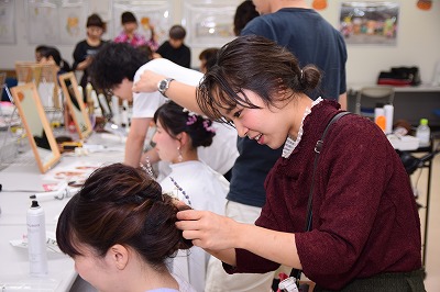 写真：gヘアアレンジをする女性美容師さん。横から