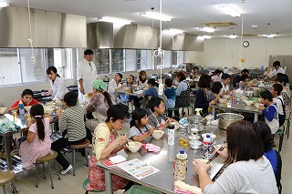 写真：うどんを食べる参加者と学生たち