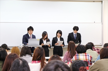 写真：4名の学生が参加者の前に立って発表を行う様子