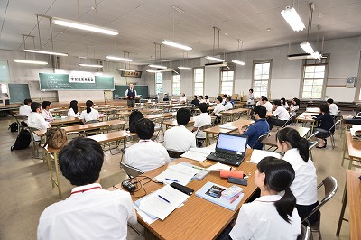 写真：統括する岡村先生とグループごとに座って聞く参加した高校生