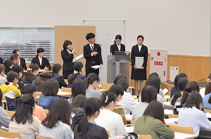 写真：卒業研究発表の様子。女子学生3名男子学生1名のグループ