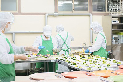 写真：大量調理中、盛り付け作業を担当する学生