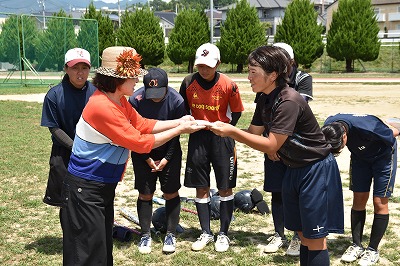 写真：激励金を手渡す教職員代表の小山先生。受け取る主将の高橋さん