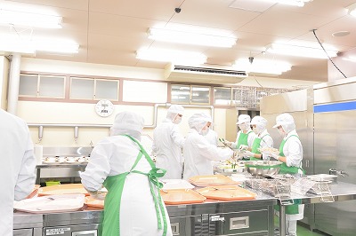 写真：大量調理中、提供手順や作業手順を確認し、作業にあたる担当学生