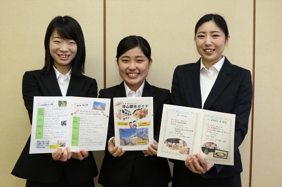 写真：パンフレットを持つ3人の学生