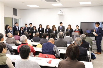 写真：里親・里子支援サークルの部員15人がの参加者の前に並んで挨拶をする様子