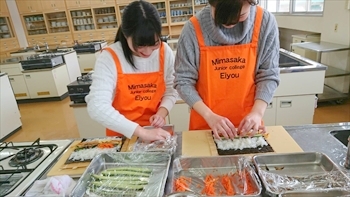 写真：手巻き寿司を巻く2名の女子学生