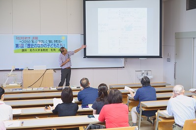 写真：公開講座でプレゼンテーションの画面を示しながら講義をする有岡先生