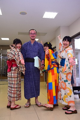 写真：g浴衣を着た岡村先生と記念撮影をする学生3人