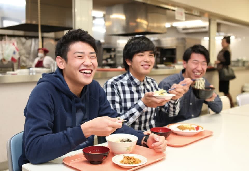 写真:学内の食堂で友達二人と学食を食べるBさん