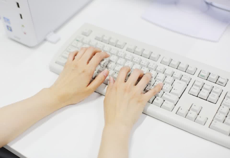 写真:コンピュータのキーボードをタイプする様子