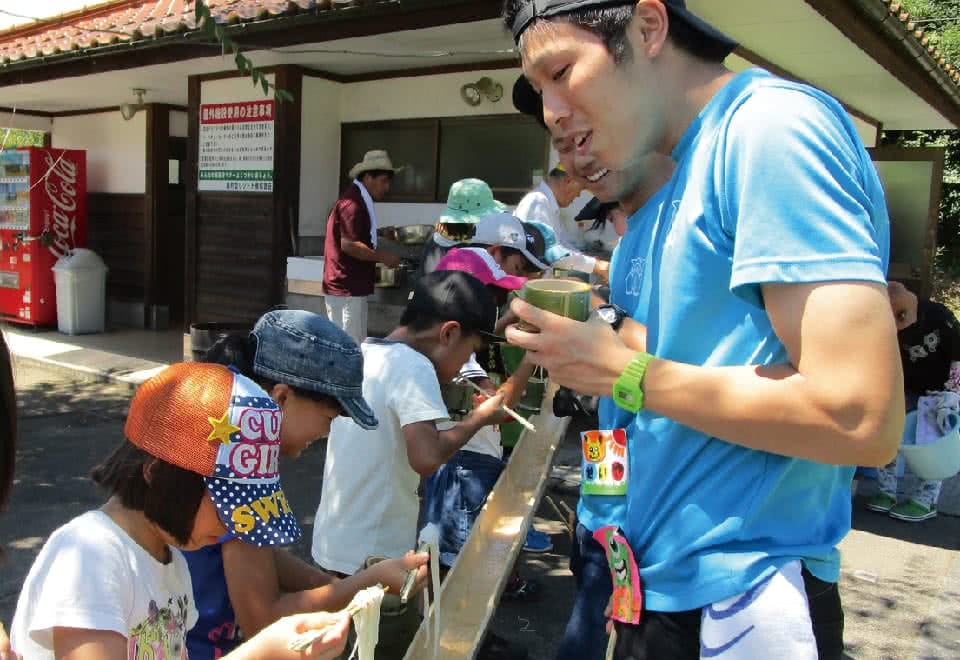 写真:児童文化研究部。子供達と流しそうめんをしている様子
