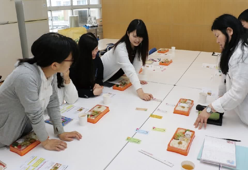 写真:机の上に色々な種類のお弁当を並べて生徒達で話し合いをしている様子