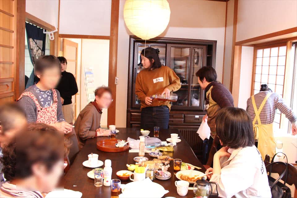 写真:食卓を囲んでご飯を食べながら語り合う学生と、認知症の方とその支援者