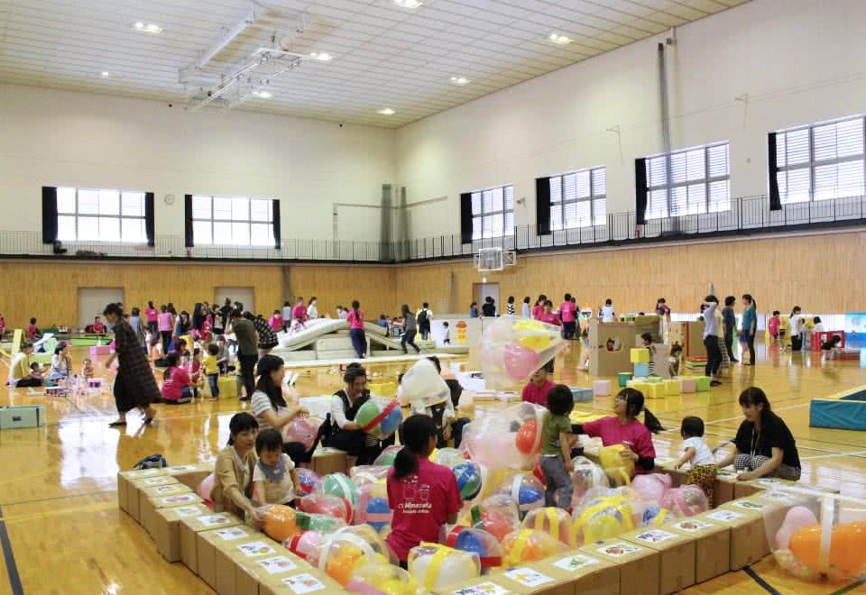 写真:体育館に設置された様々な手作りの遊具で遊ぶ大勢の親子と対応する学生たち