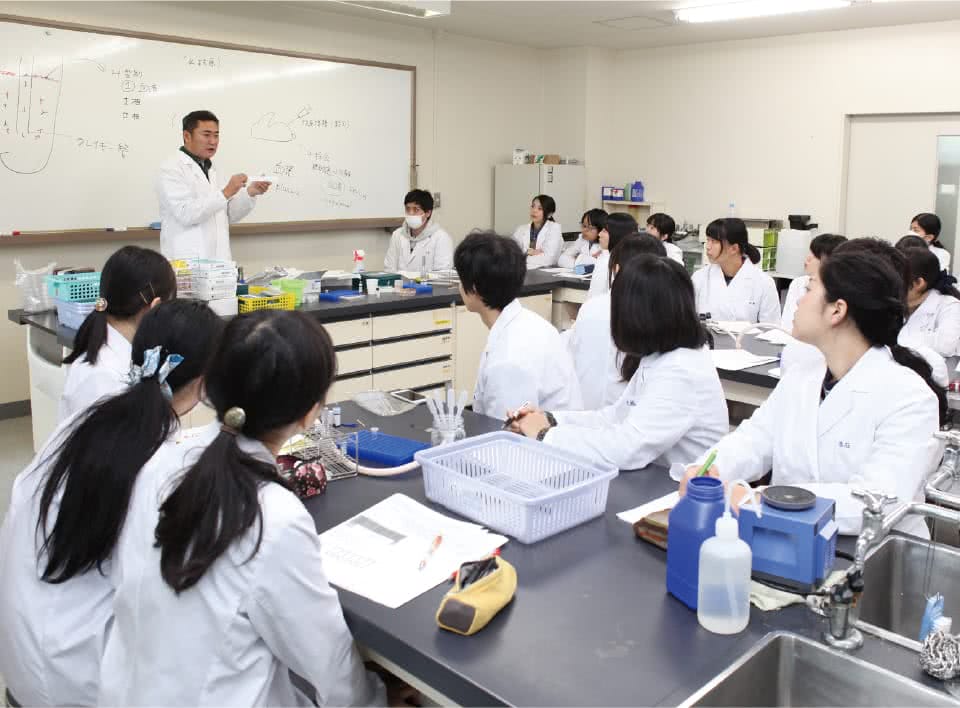 写真:男性教員と生徒たちが実習(講義)を受けている様子。