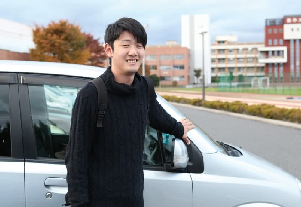 写真:自家用車の前に立つCさん