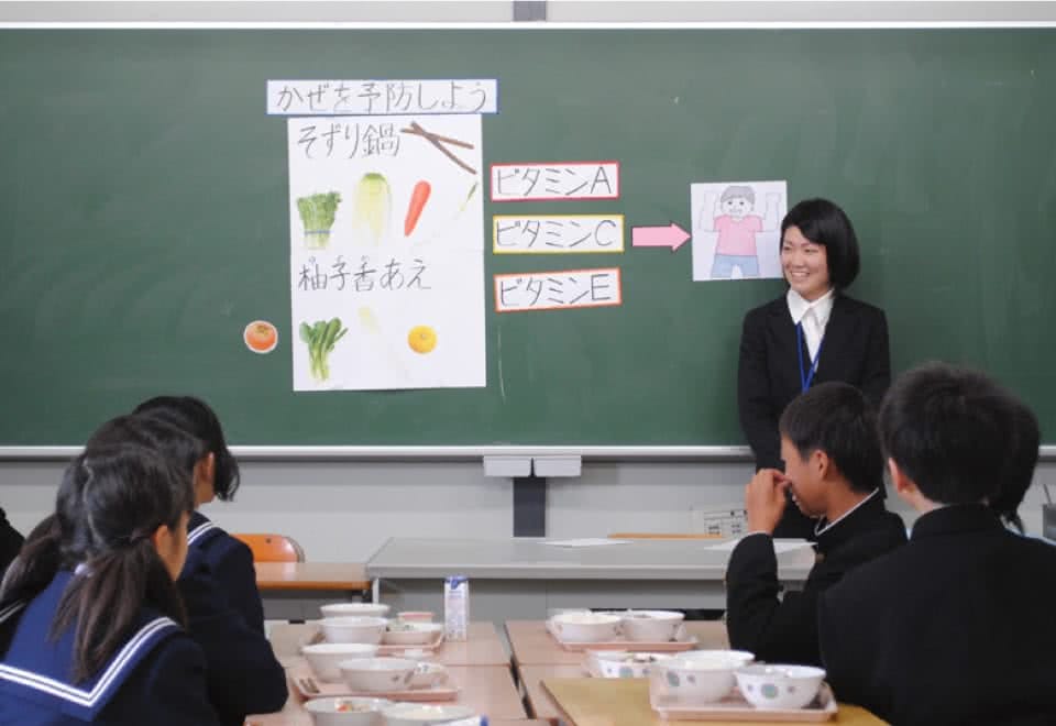 写真:小学校・中学校の黒板に自作の教材を貼って、給食時間の指導を行っている様子