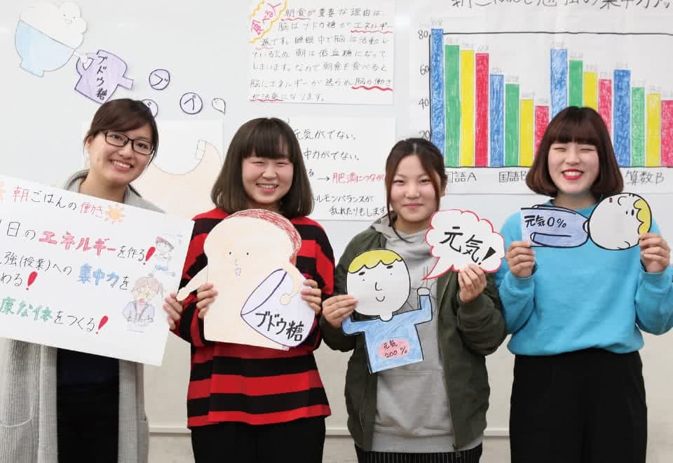 写真:女性が4名手作りの資料を持ち3分間スピーチの練習をしている様子