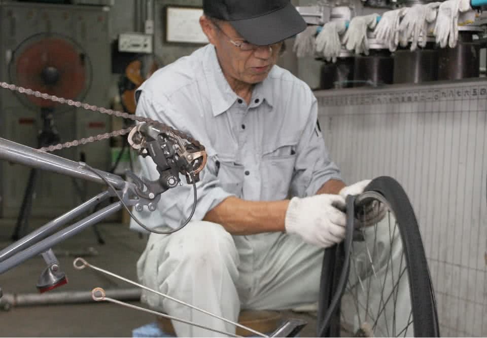 写真：自転車の修理をする男性の校務員さん
