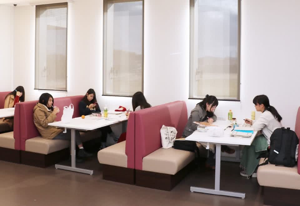 写真:オープンコモンズのダイナーテーブルでグループごとに向かい合わせに座る学生たち。勉強や休憩など思い思いに過ごしている。