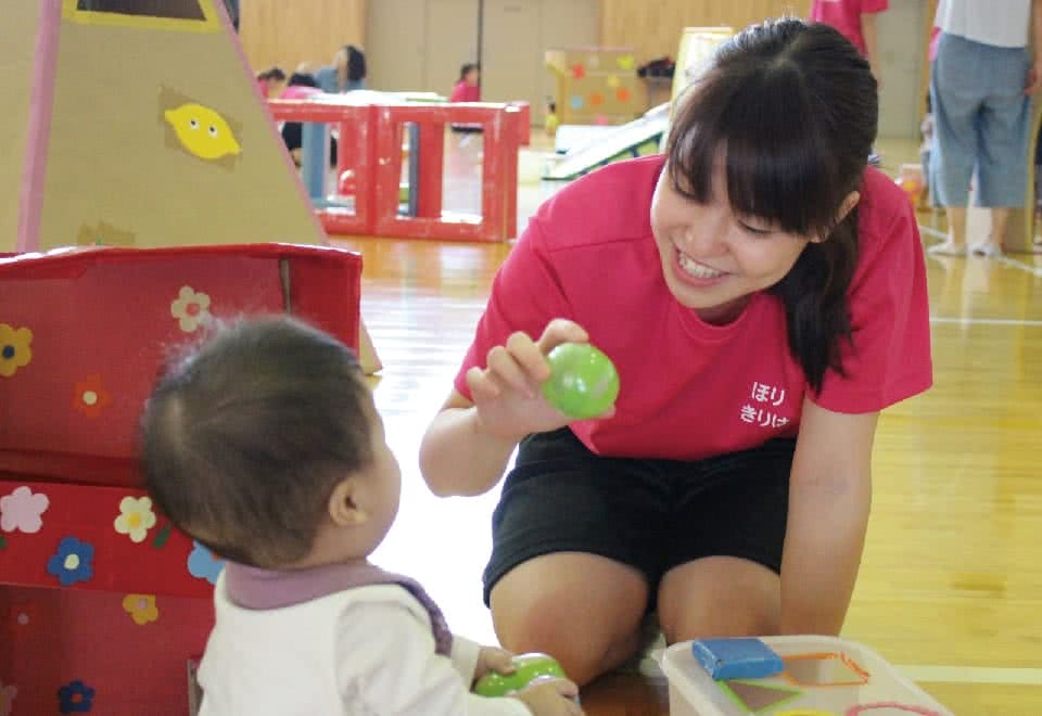 写真:みまさか子育てカレッジ。女性が赤ちゃんにボールを見せて遊んでいる様子