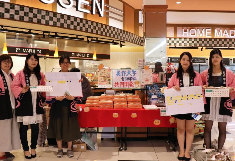 写真:マルイノースランド店にて実施した共同開発弁当販売キャンペーンでハッピを着て活動する人見研究室の学生たちと人見准教授