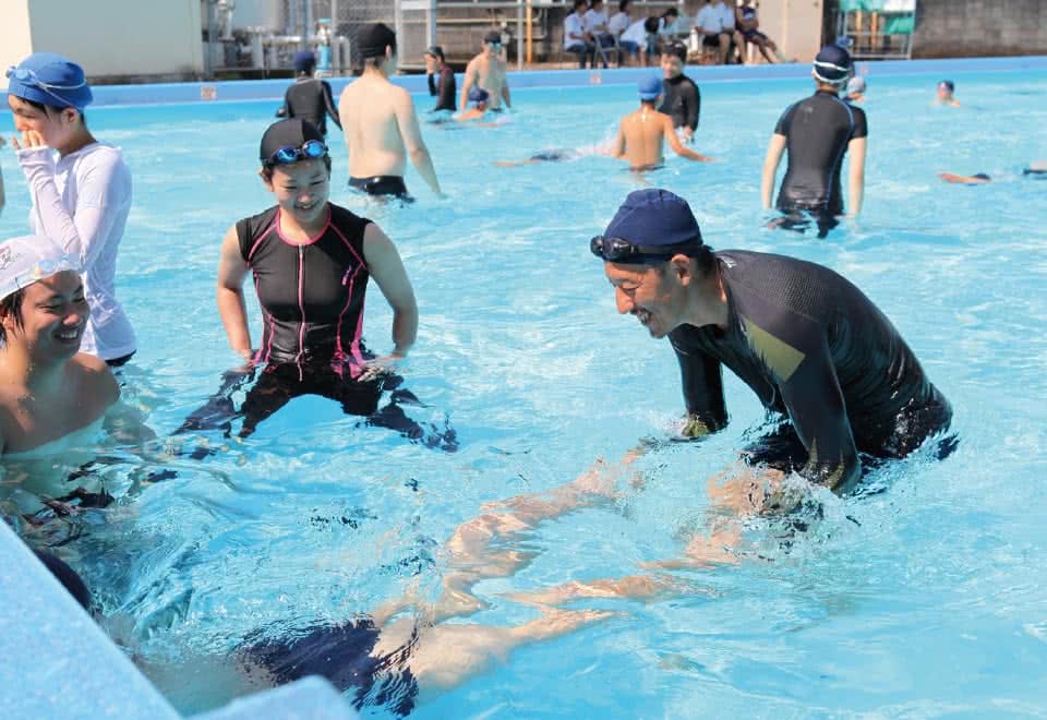 写真:体育科教育法。小学校でプールの中で泳ぎの指導をしている様子